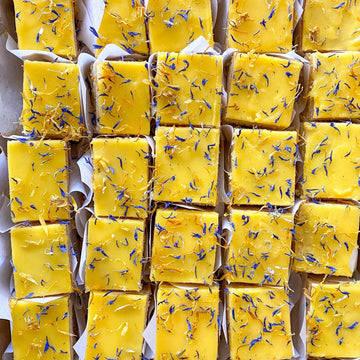 Top-down view of several square lemon cake slices, each wrapped in parchment paper.