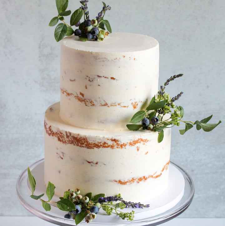 A two-tier cake decorated with two plumes of fresh berry branches.