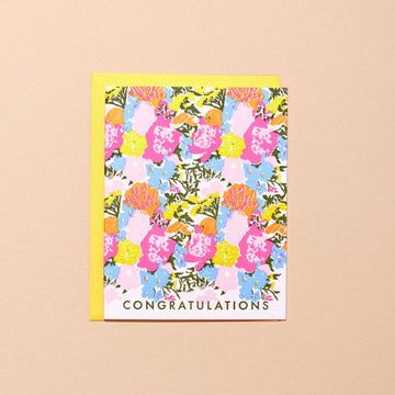 A card printed all over with a colorful flower pattern and the word "CONGRATULATIONS" at the bottom. The card comes with a yellow envelope.