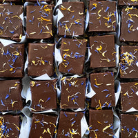 Top-down view of several square chocolate cake slices, each wrapped in parchment paper.