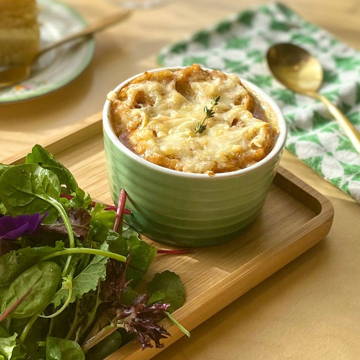 A bowl of French onion soup and a side salad.