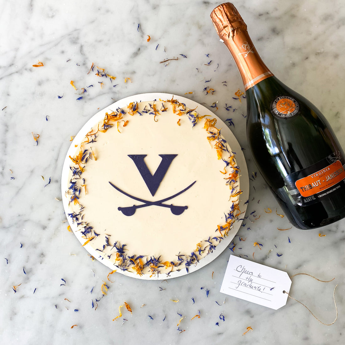 UVA graduation cake by Cake Bloom featuring a stenciled blue "V" and cavalier blue and orange edible flowers. Available for pick-up and local 