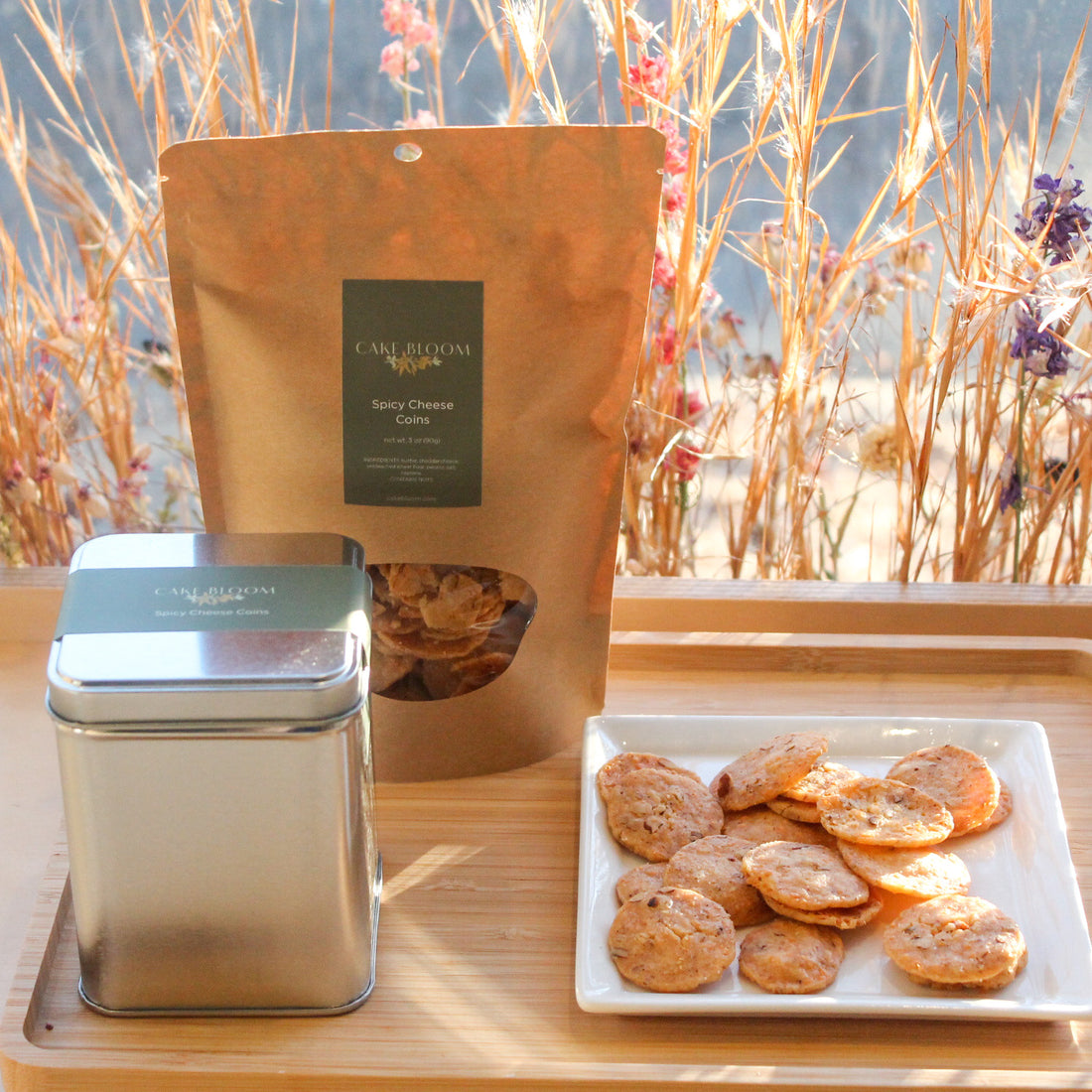 A plate of spicy cheese coins, placed beside a bag and a metal canister of the same.