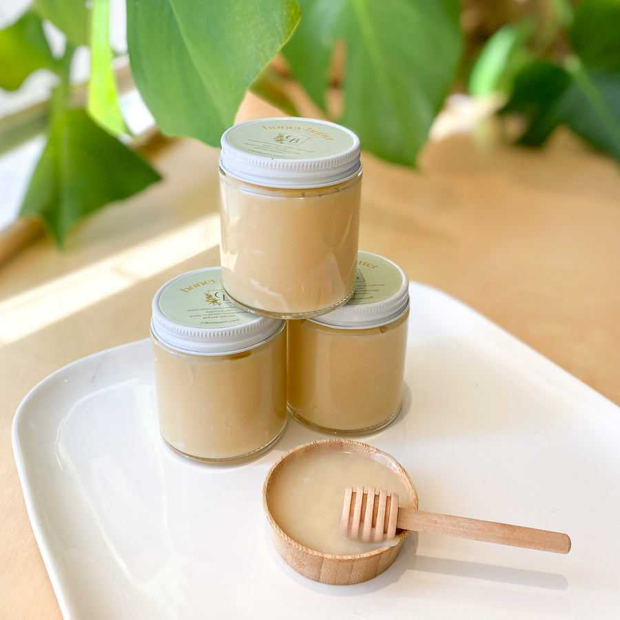 Three jars of honey butter arranged next to a small bowl of the same.