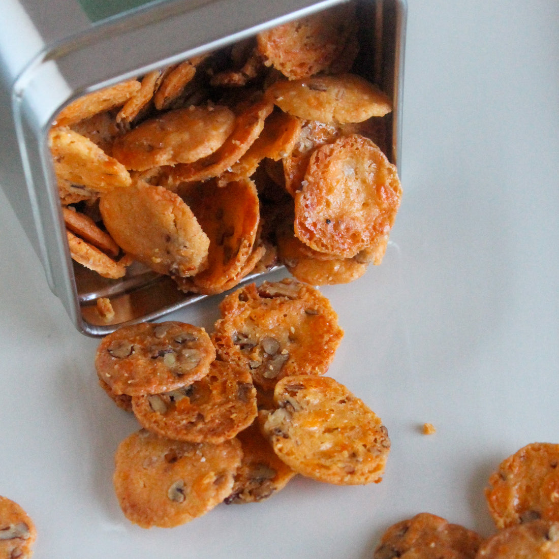 Close-up of spicy cheese coins spilling from an overturned canister.