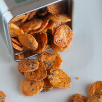 Close-up of spicy cheese coins spilling from an overturned canister.